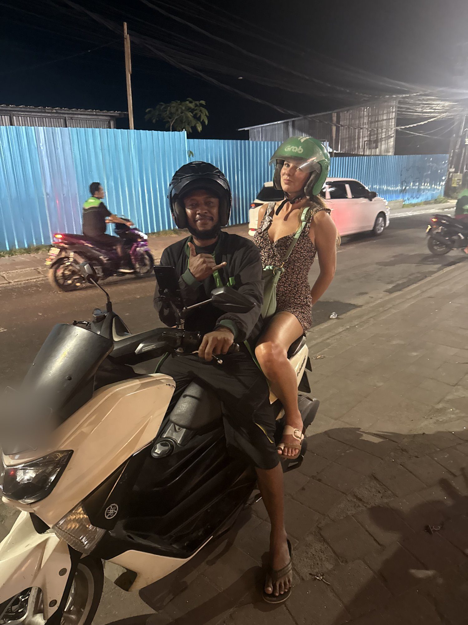 Woman riding pillion on a Grab motorbike taxi in Uluwatu at night